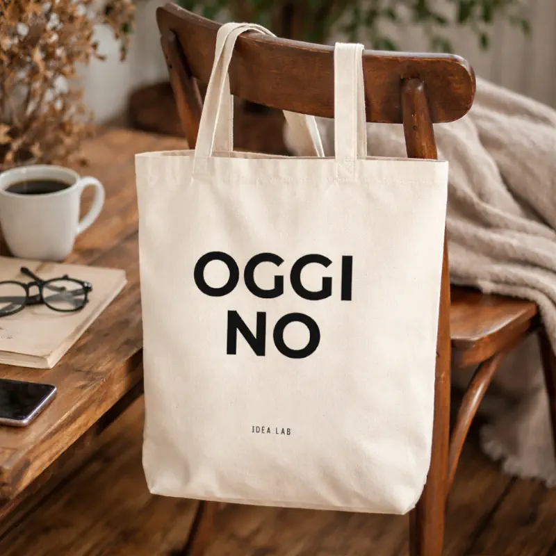 Shopper personalizzata OGGI NO in cotone naturale Idea.lab appoggiata su sedia in ambiente domestico