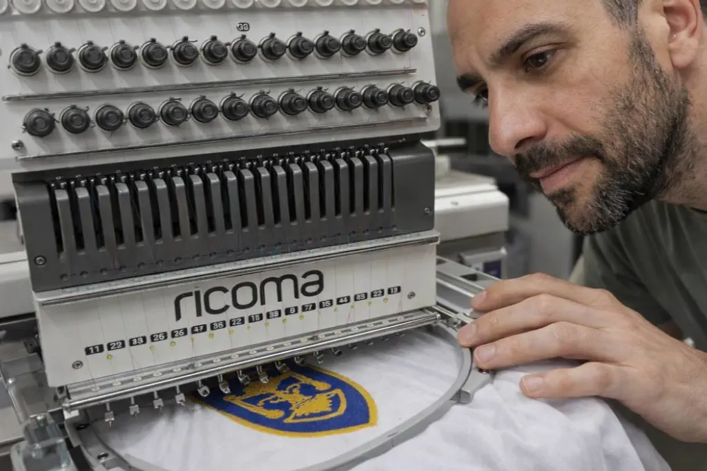 Operatore al lavoro nel laboratorio ricamo Ivrea durante la produzione.